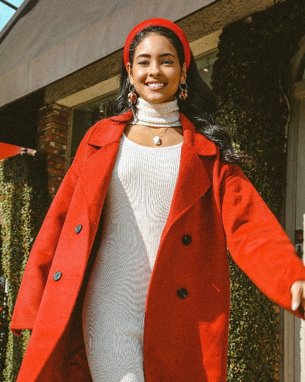 Woman wearing a red coat and beret standing outdoors.