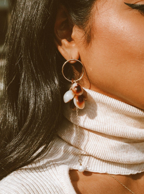 Close-up of a person wearing a hoop earring with a bee and flower design.