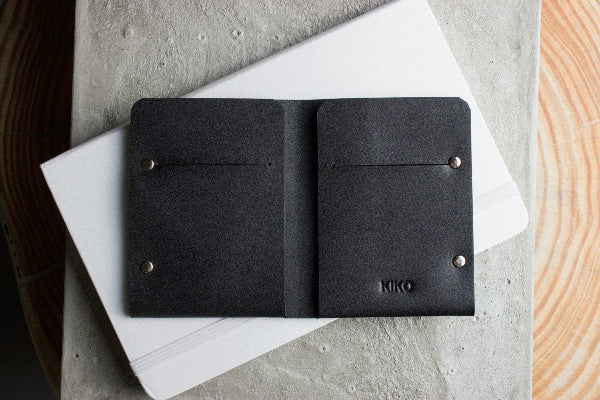 Black leather wallet with 'Kiko' branding on a white surface