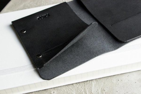 Black leather wallet with brand logo on a light gray surface