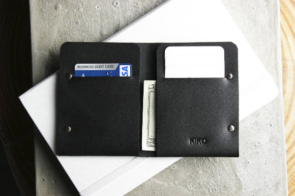 Black leather wallet with cards and money on a light surface