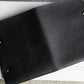 Black leather notebook with metal rings on a white surface
