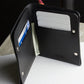 Black wallet with cards and money on a white surface