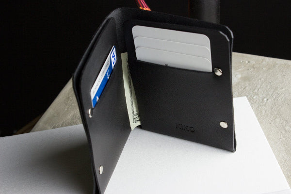 Black wallet with cards and money on a white surface