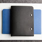 Black notebook with blue cover on a white surface