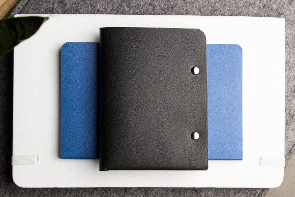 Black notebook with blue cover on a white surface