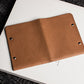 Brown leather notebook on a white surface with a black textured background