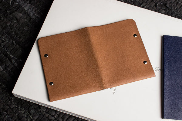 Brown leather notebook on a white surface with a black textured background
