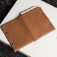 Brown leather notebook cover on a white book with a black textured background