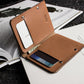 Brown leather wallet with phone and card holder on top of an open book