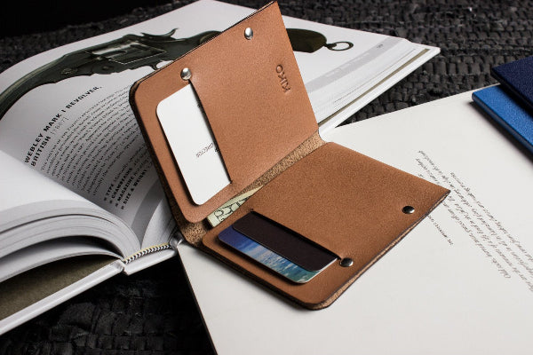Brown leather wallet with phone and card holder on top of an open book