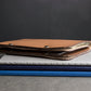 Stack of leather-bound books with a brown leather cover on a gray surface against a dark background
