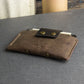 Brown leather wallet with gold buttons on a gray surface