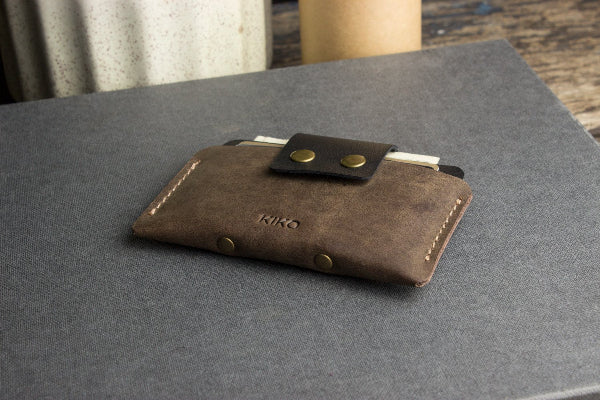 Brown leather wallet with gold buttons on a gray surface