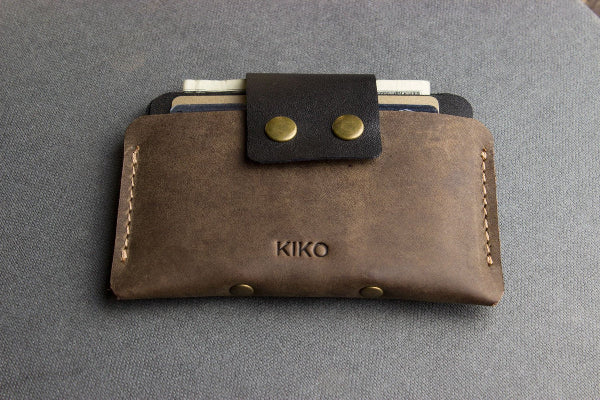 Brown leather wallet with gold accents on a gray background