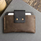 Brown leather wallet with black flap on a gray surface