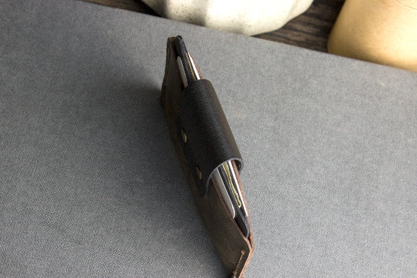 Close-up of a leather wallet with metallic accents on a gray surface