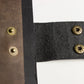 Close-up of brown leather and black fabric with gold buttons on a white background