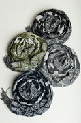 Four folded scarves in green, black, and gray on a white background