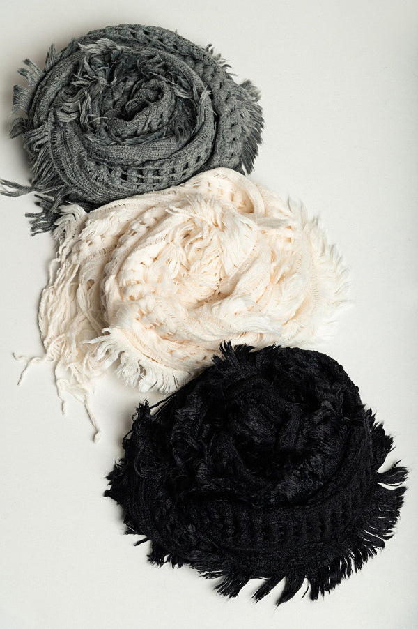 Three scarves in gray, white, and black on a light gray background