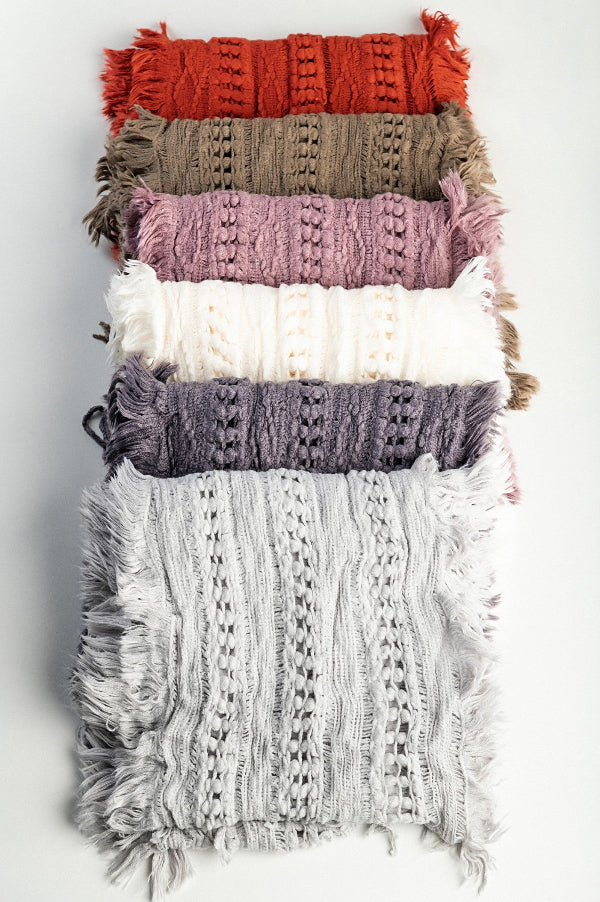 Stack of textured scarves in various colors on a light gray background