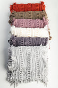 Stack of textured scarves in various colors on a light gray background
