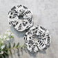 Two white scrunchies with black abstract patterns on a light gray background.