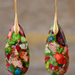 Colorful teardrop-shaped earrings with gold hooks on a blurred background
