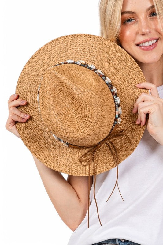 Woman holding a straw hat with decorative band against a white background