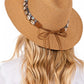 Brown straw hat with decorative band and bow on a white background
