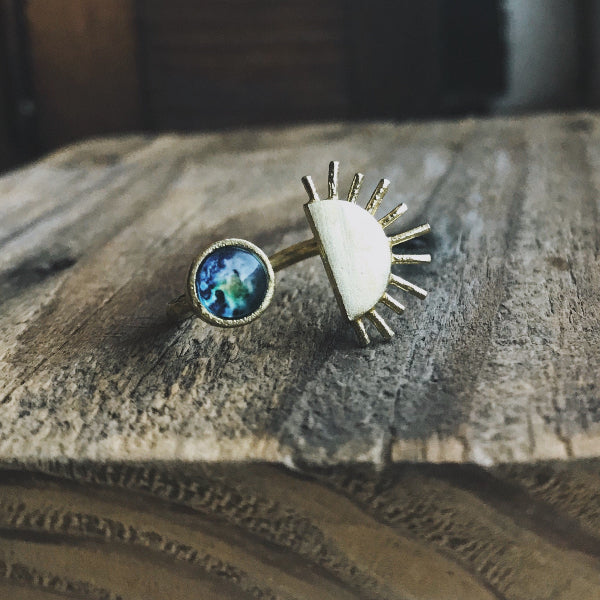 Ring with blue gemstone and white stone on a wooden surface