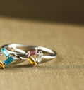 Silver ring with colorful gemstones on a beige fabric background