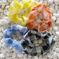 Four colorful scrunchies on a textured white surface