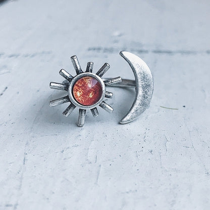 Silver sun and moon earrings on a textured surface