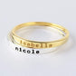 Two stacked rings, one gold and one silver, with engraved names on a light gray background.
