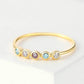 Gold ring with five round gemstones on a light background