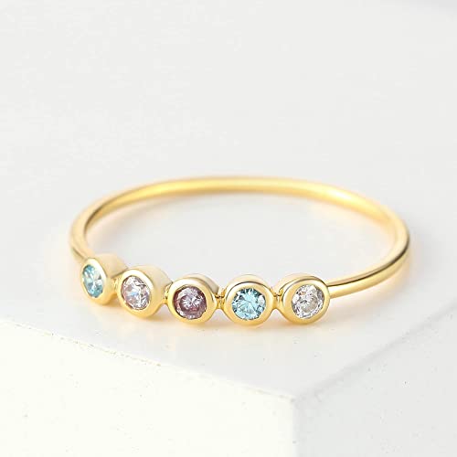 Gold ring with five round gemstones on a light background