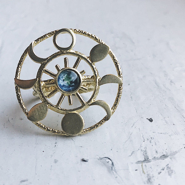 Gold ring with a central blue gemstone on a white marble surface