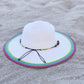 white and multicolor woven summer hat with beaded band resting on beach