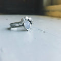 Silver ring with a blue gemstone on a light gray surface