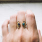 Gold earrings with gemstones on a hand against a light background