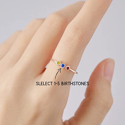 Ring with birthstones on a finger against a light background
