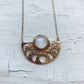Gold necklace with a circular pendant on a textured white background