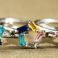 Silver ring with colorful gemstones on a beige background