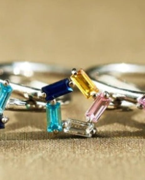 Silver ring with colorful gemstones on a beige background