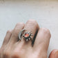 Silver ring with sun and moon design on a finger against a neutral background