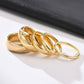 Set of gold rings on a white surface with a black fabric background