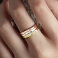 Three stacked rings with engraved names on a hand