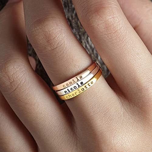 Three stacked rings with engraved names on a hand
