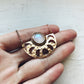 Gold necklace with a moonstone pendant held by a hand on a light background